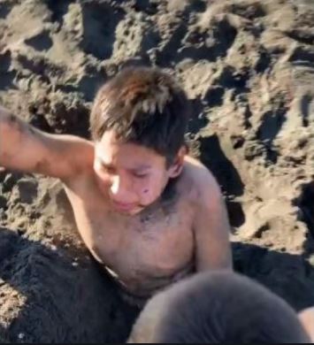 niño enojado al ser enterrado en la arena 